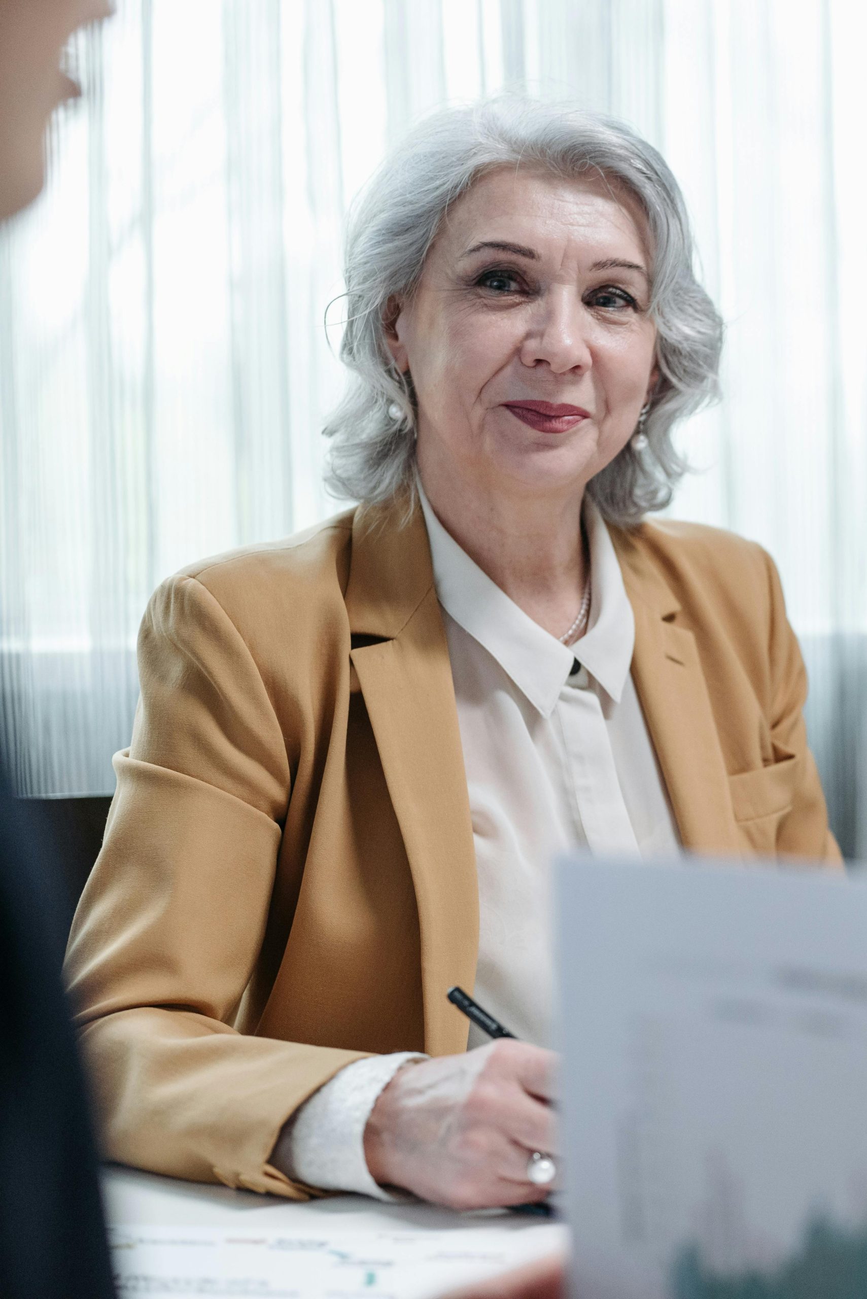 Senior businesswoman with gray hair smiling during a professional meeting.